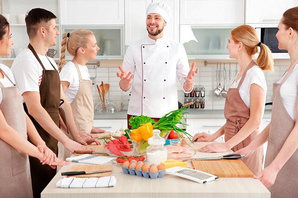 Cocinero habla a mujeres y hombres en la cocina