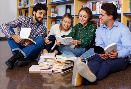 Grupo de jóvenes, reunidos en la biblioteca, están compartiendo sus impresiones con el autor y otros aficionados en el club de lectura que Colsubsidio organiza para los trabajadores de las empresas afiliadas.