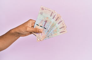Una mano sosteniendo billetes colombianos.