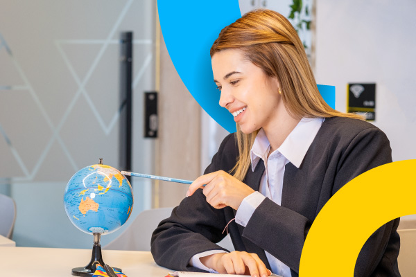 Estudiante sonríe mientras estudia con un globo terráqueo en un ambiente académico.