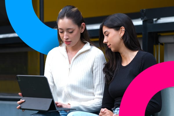 Dos mujeres revisan contenido en un portátil durante una clase práctica.