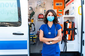 Una paramédica posa a lado de una ambulancia.