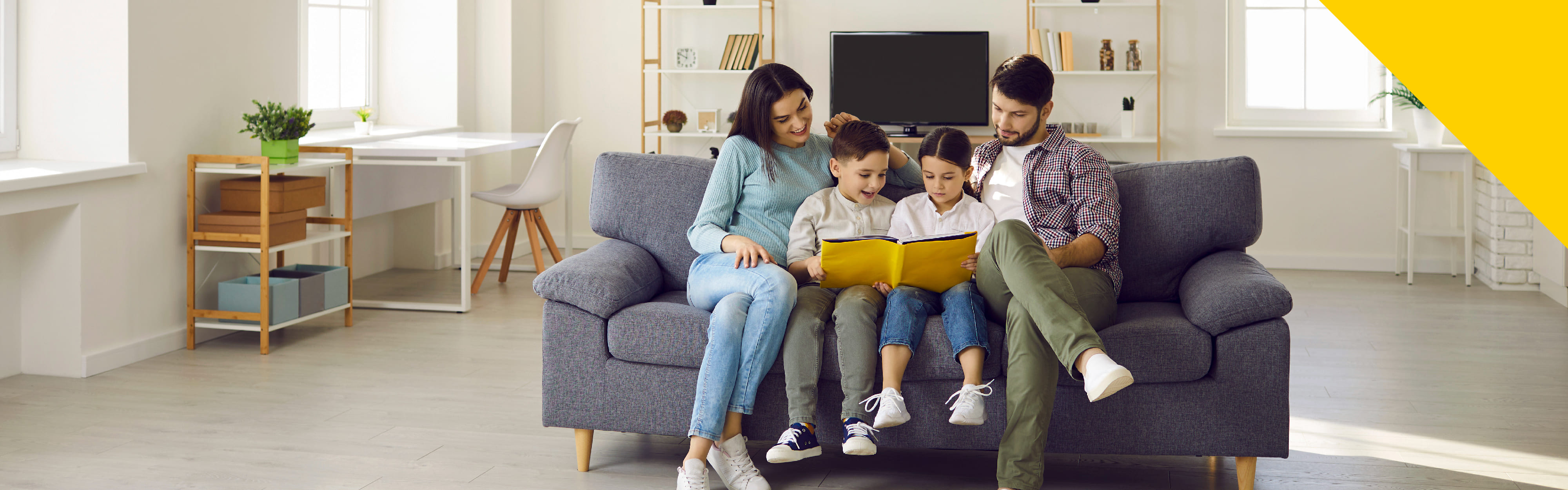 Padre, madre e hijos sentados en un sofá y leyendo un libro de la Biblioteca Digital de Colsubsidio.